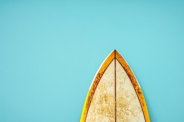 A well used surfboard set against a plain bright blue backdrop