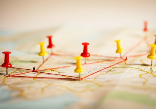 Colorful pushpins on a map with red string highlighting travel route