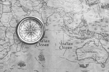 Classic round compass on background of old vintage map of world