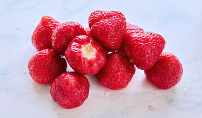 A luscious pile of fresh strawberries glistens with dew, inviting summer indulgence in a bright kitchen
