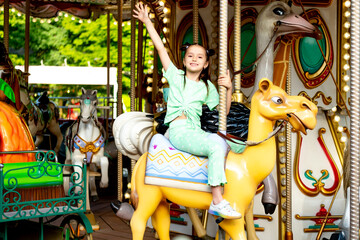 a child in an amusement park rides a carousel and enjoys the International Children's Day in...