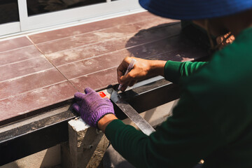 Male worker measuring iron with metal ruler in building site.