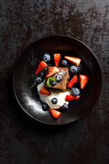 Decadent chocolate dessert with fresh strawberries, blueberries, vanilla ice cream, and a dusting of powdered sugar
