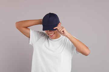 Smiling man in stylish baseball cap on grey background. Mockup for design