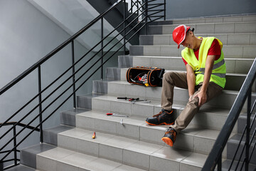 Accident at work. Injured man on stairs indoors. Space for text