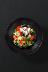 A fresh vegetable salad with feta cheese, crisp greens, and a light dressing. Restaurant-style presentation, captured under studio lighting for vibrant colors. Top view