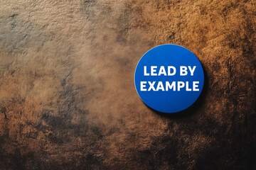 Lead by example message written on blue badge on dark background. Conceptual lead by example symbol. Copy space.