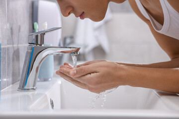 Man washing his face over sink in bathroom, closeup