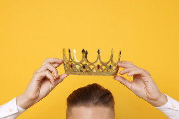 Man wearing luxury crown on orange background, closeup