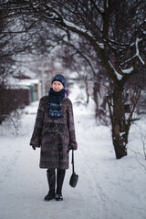 A woman in a karakul fur coat walks along a snow-covered path, surrounded by deep snowdrifts that blanket everything in sight.