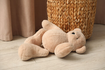 Teddy bear near basket on floor at home