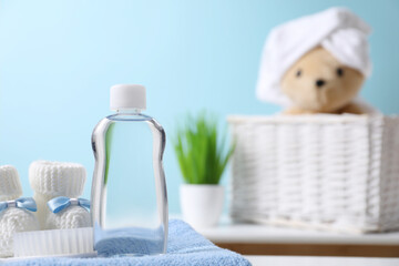 Baby oil in bottle, booties and brush on towel against blurred background