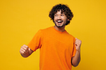 Young smiling fun happy Indian man wear orange t-shirt casual clothes doing winner gesture...