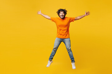 Full body young shocked surprised happy Indian man he wear orange t-shirt casual clothes jump high...