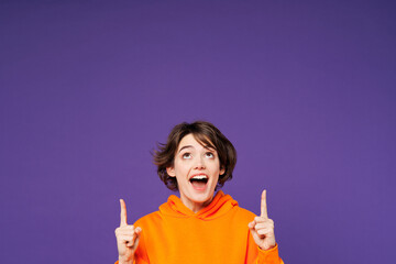 Young shocked surprised happy woman she wear orange hoody casual clothes point index finger...