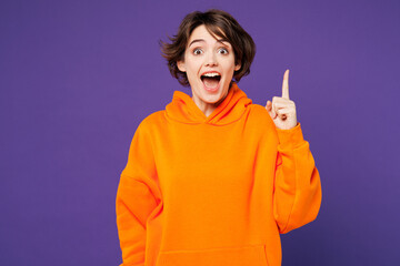 Young proactive shocked smart happy Caucasian woman wear orange hoody casual clothes holding index...