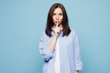 Young secret Caucasian woman she wears shirt casual clothes say hush be quiet with finger on lips...