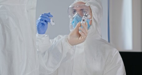 A medical professional is preparing a vaccine with protective gear for safety and hygiene