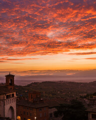 Beautiful dawn sky with orange clouds over the old city of Perugia, with medieval bell tower and Umbria countryside in the background