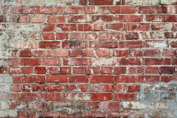 Fototapeta premium Weathered red brick wall with cement patches. AI generated
