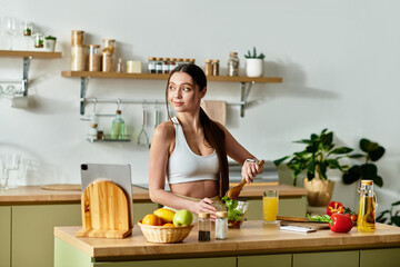 Young woman in sportswear enjoys cooking a fresh salad in a bright kitchen