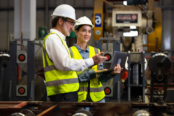 Trainee. caucasian Factory worker training to  apprentice colleague on production line in Heavy...