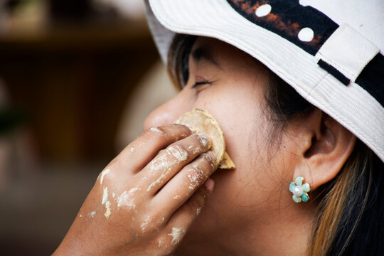 Local Thai Mon children girl using wooden stamp thanaka powder makeup on cheek of women traveler people travel visit join event tribe mon annual celebration at Wat makham temple in Ratchaburi Thailand
