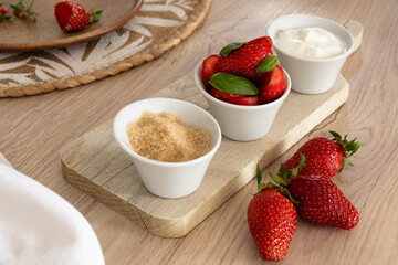Fraises fraîches avec sucre et crème fraîche sur planche en bois