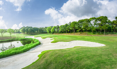 Scenic view of a golf course with bunker and lake in summer