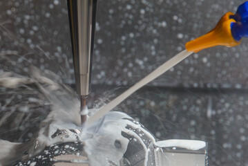 The CNC milling machine cutting  the mold part with liquid coolant method.