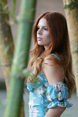Linda modelo ruiva posando para uma sessão de fotos em um parque ao ar livre, explorando...