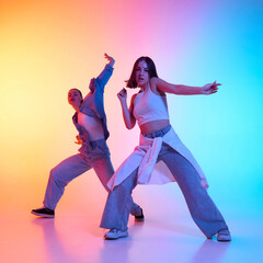 Hip hop dancers in casual attire striking dramatic poses against bold neon gradient lighting. Concept of urban movement, youth expression, passion for dance, street culture, freestyle choreography.
