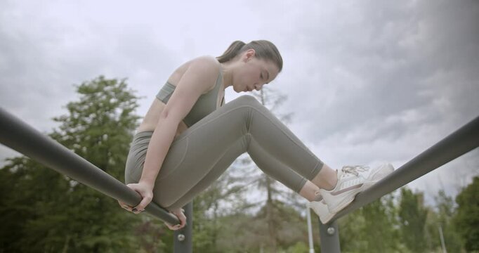 Three friends working out together in an outdoor gym in a park. They're doing fitness exercises on the parallel bars.