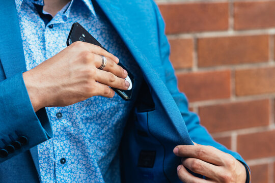 man putting phone into jacket pocket