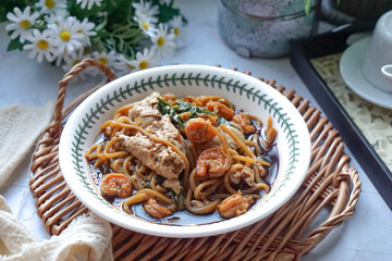 A  bowl of Mee Hailam, with tender noodles, shrimp, chicken, vegetables, and a rich, aromatic broth.