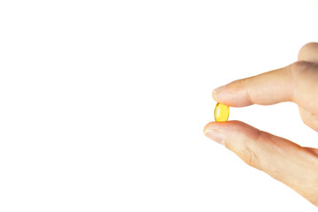 Fingers holding one yellow pill of vitamin D supplement, used for a healthy lifestyle. Perfect...