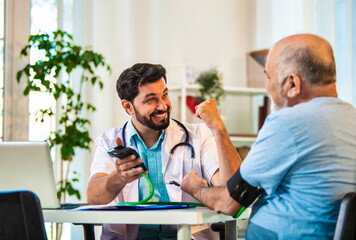 Fototapeta premium Young Indian doctor monitors BP of an elderly patient in a cozy clinic, ensuring proper diagnosis