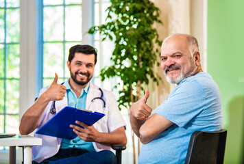 Indian Doctor, elderly patient share a thumbs-up in a cozy clinic, celebrating healthcare success