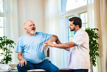 Obraz premium Indian Senior retired male patient undergoing physiotherapy assessment for shoulder, neck pain