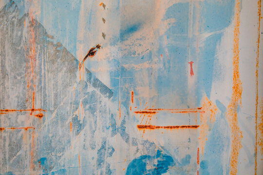 Textures and patterns of rust and peeling paint on the corrugated side of an old shipping container