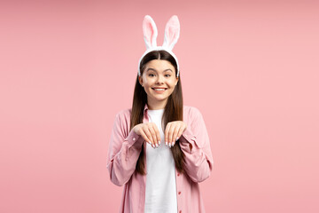 Young woman wearing bunny ears headband is making bunny paws with her hands and smiling