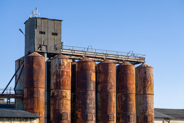 old dilapidated grain elevator in the countryside. rusty and abandoned grain elevator against the blue sky.