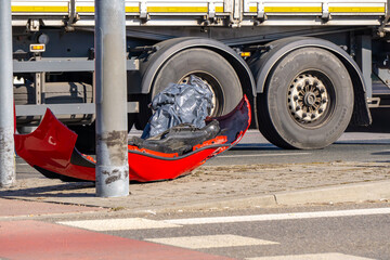 red car bumper lying on the sidewalk after a road collision with a truck. car accident. damaged elements.