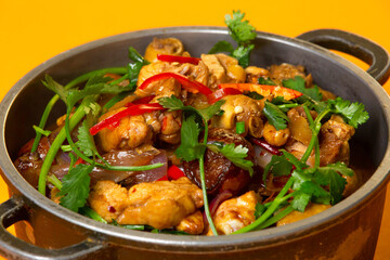Chinese Spicy Chicken Pot topped with coriander served in pot isolated on orange background side view of hong kong food