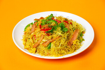 Singapore Fried Rice Noodles including rice vermicelli stir fried with ham, vegetables, cilantro and red chilies served in plate isolated on orange background side view of hong kong food
