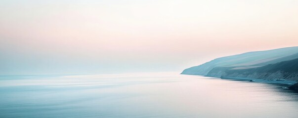 The calm ocean meets a coastline under a soft pastel sky