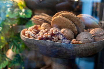 Shelled walnuts and whole walnuts with organic cereal crackers in wooden bowl behind glass