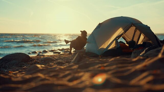 Lonely traveler on sea beach, sitting in chair near tent, solitude in nature. Local tourism and backpacking, unity of person and nature, man relaxing and admiring sea view, camping on ocean coastline