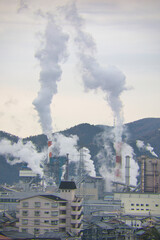 煙突から白い煙を出す大きな工場