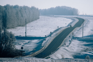 A winter road leading through a snowy forest